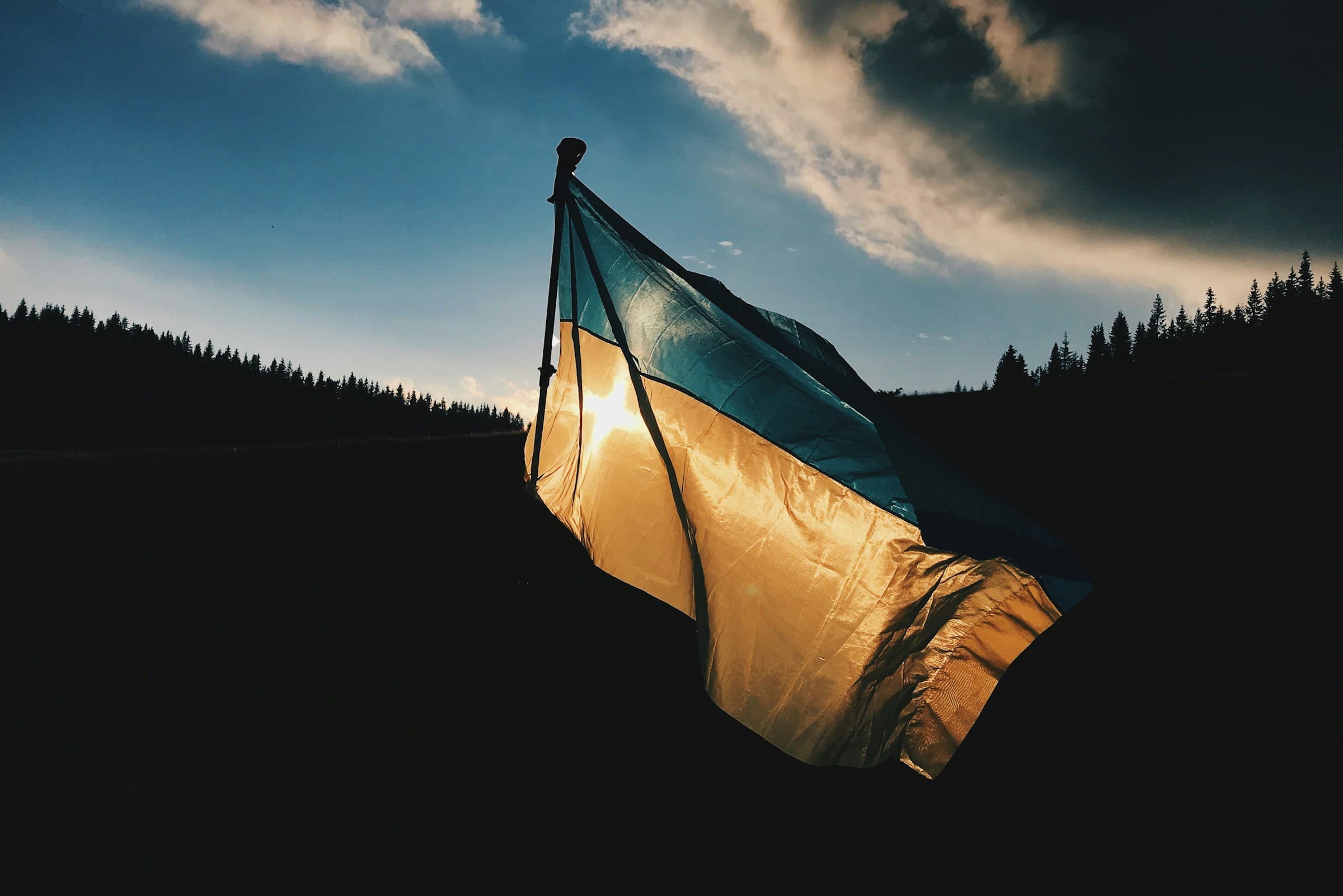 A Ukrainian flag backlit by the setting sun