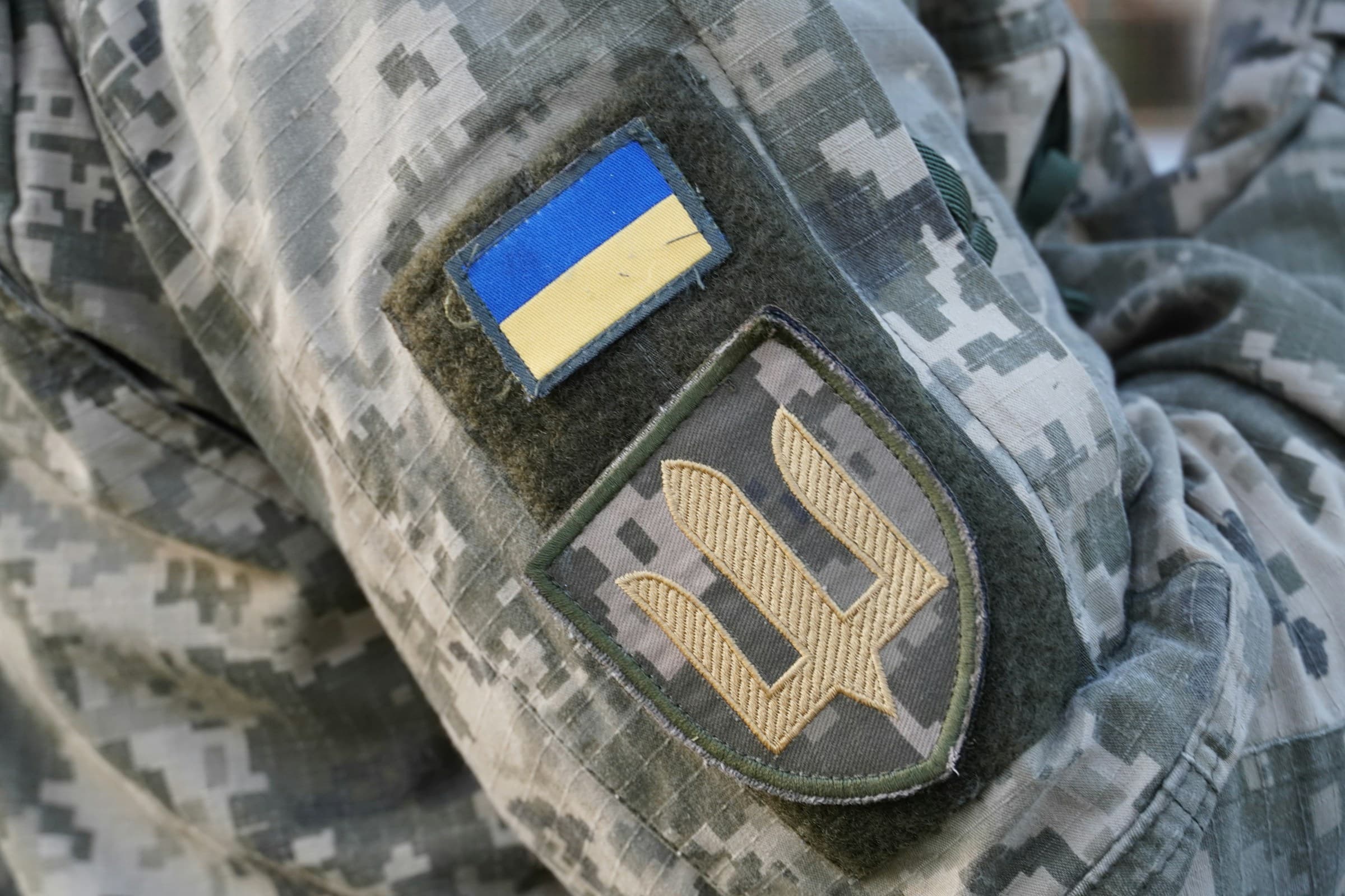 Close view of a Ukrainian soldier's uniform showing the national flag and trident patch